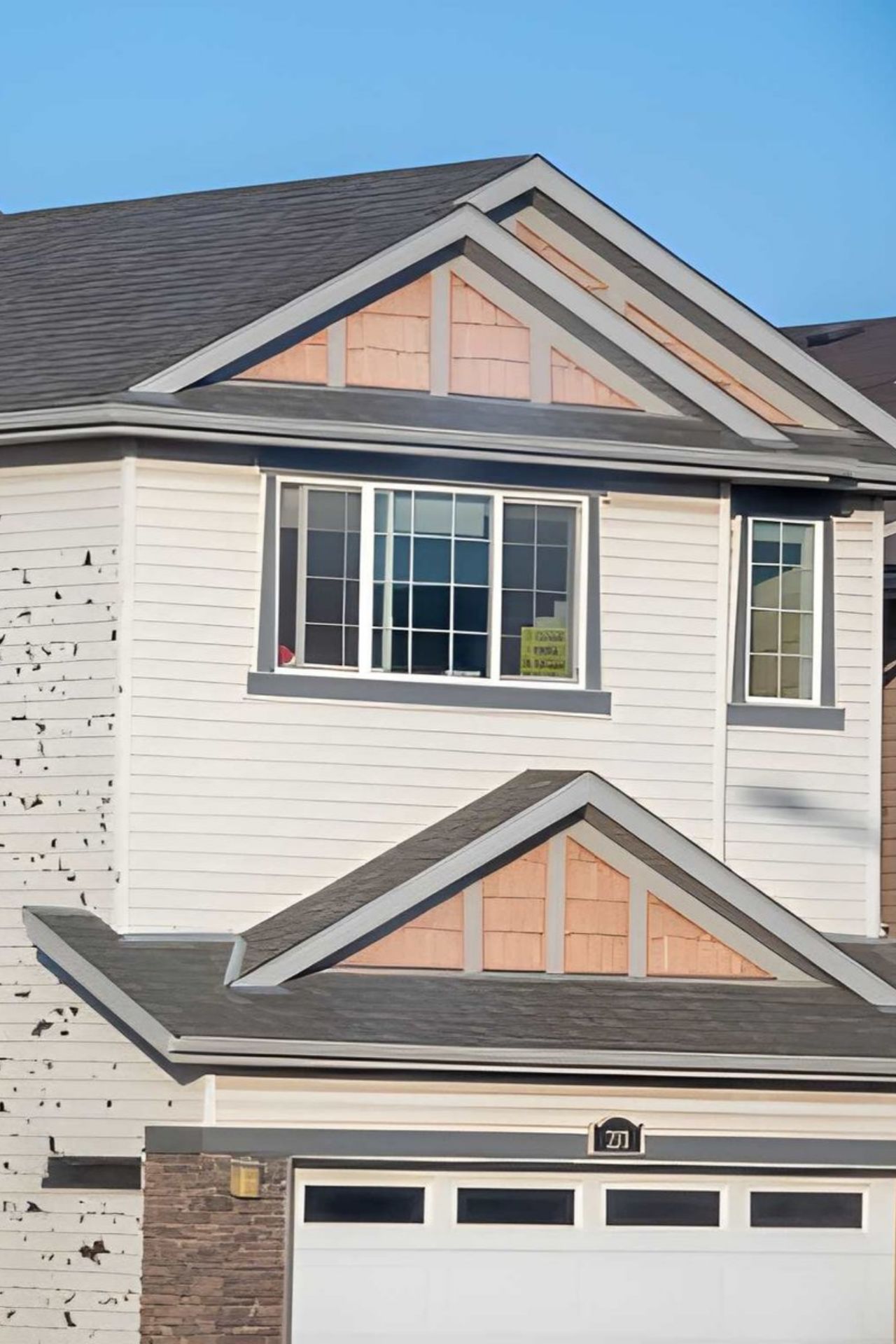 Damaged siding on a house with a "For Sale" sign in the window.