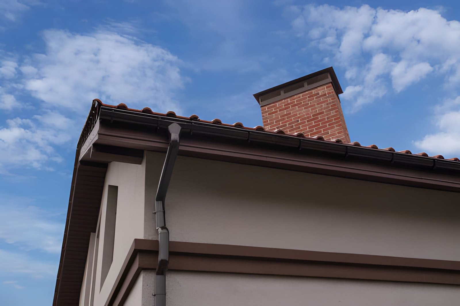 Home exterior with new brown roof, chimney, and gutters
